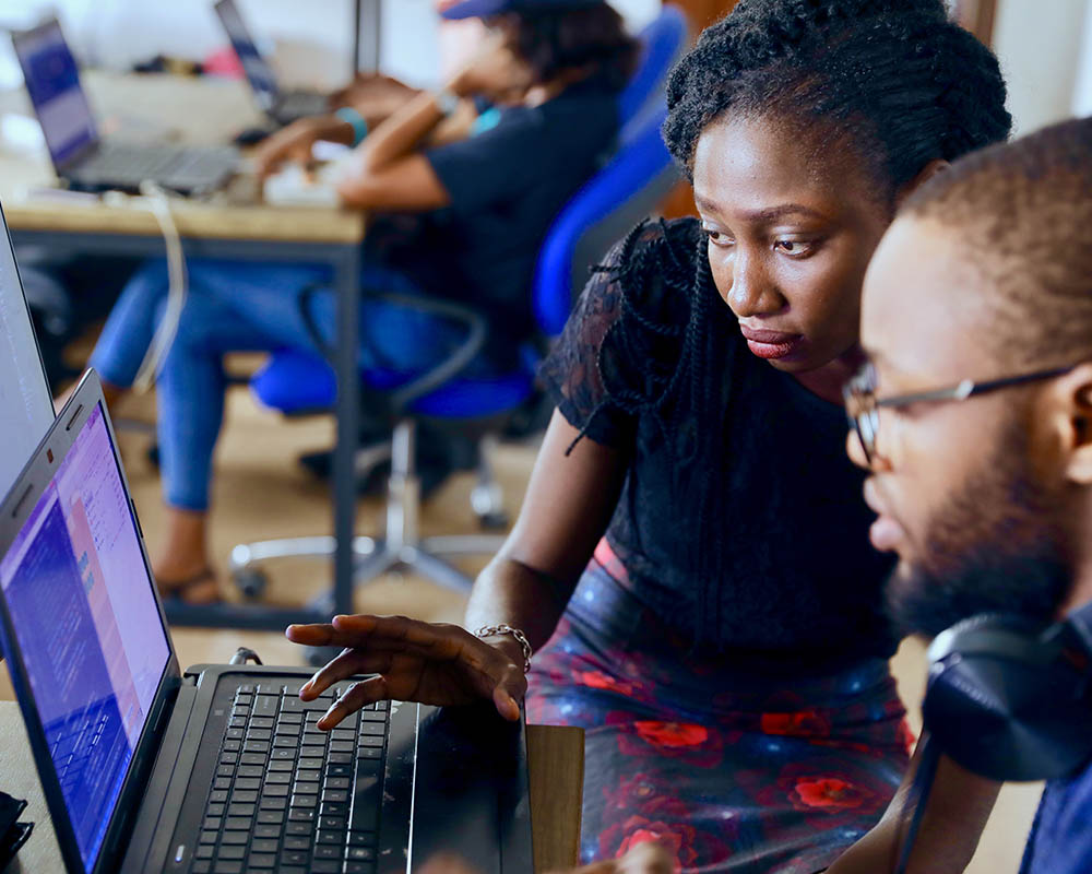 2 people collaborating in front of a laptop